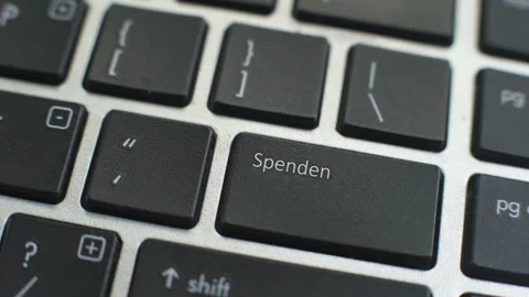 Donate in German button on computer keyboard, female hand fingers press key Stock Footage 97827080