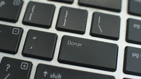 Donate in Spanish button on computer keyboard, female hand fingers press key Stock Footage 97828020