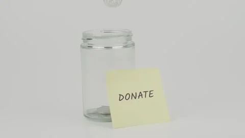 Donate text or word on yellow notes on empty jar hand inserting coin Stock Footage 307071380