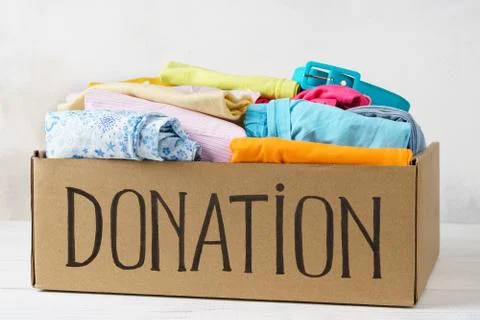 Donation box with various clothes on a table. Stock Photos