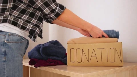 Donation box with winter clothes on the table. A woman puts things in a box. Stock Footage 199119907