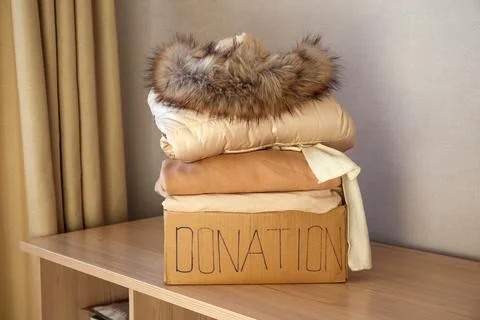 Donation box with winter clothes on the table. Stock Photos