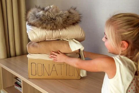 Donation box with winter clothes on the table. Stock Photos