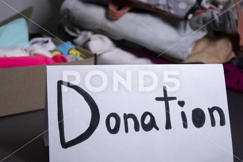 'donation' sign handwritten with black letters. A box with clothes and ...