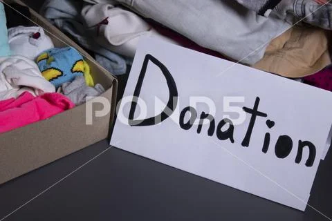 'donation' sign handwritten with black letters. A box with clothes and ...