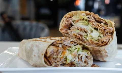 Doner kebab wrap cut in half on a white plate Stock Photos