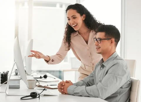 Dont be scared to ask for help. two young colleagues using a computer in an Stock Photos