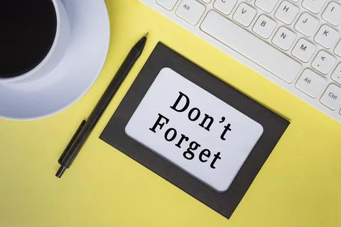 Don't forget text on white note with keyboard, pen and coffee cup. Stock Photos