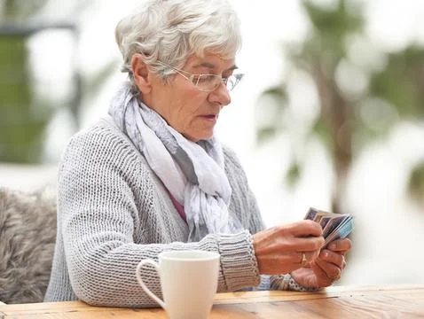 Dont hate the player, hate the game. a senior woman holding a stack of cards in Stockfoto's