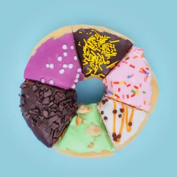 A donut consisting of slices of six different donuts on a pale blue background Stock Photos