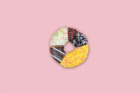 A donut divided into different segments on a pink background,top view Stock Photos