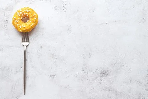 Donut on a fork, flat lay on grey background Stock Photos