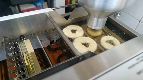 Donut making process of freshly frying dough ring dropped into cooking oil at Stockbeeldmateriaal 308518907