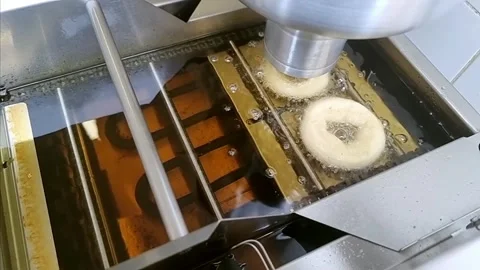 Donut making process of freshly frying dough ring dropping into cooking oil at Stockbeeldmateriaal 308518975