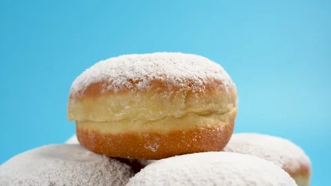 A donut with powdered sugar is placed on top of a stack of other donuts. Stock Footage 304752292