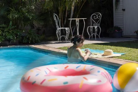 Donut-shaped inflatable float drifting on turquoise pool water near beach ball Stock Photos
