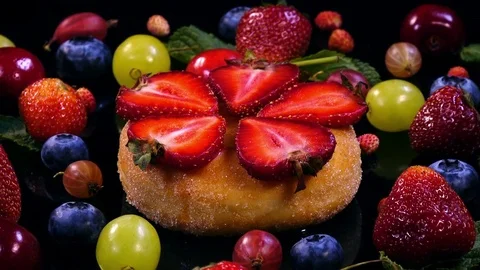 Donut with sliced strawberry and mixed berries and fruits rotates in 4K Stock Footage