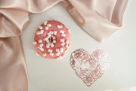 Donut with splashes, on a white background, with a lacy heart and silk fabric Stock Photos