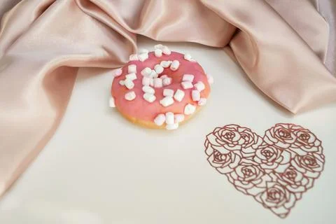 Donut with splashes, on a white background, with a lacy heart and silk fabric Stock Photos