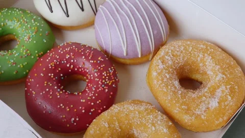 Donuts with different colorful icing designs arranged in a box. Stock Footage 312495501