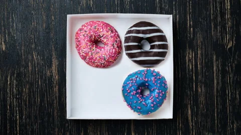 Donuts of different colors changing in box. Stop motion. Four glazed sweet donut Stock Footage 159585389