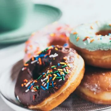Donuts of different flavors accompanied by a cup with coffee for breakfast. Stock Photos