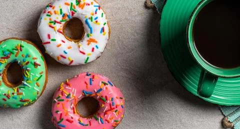 Donuts of different flavors accompanied by a cup with coffee for breakfast. Stock Photos