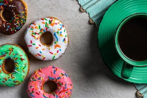Donuts of different flavors accompanied by a cup with coffee for breakfast. Stock Photos