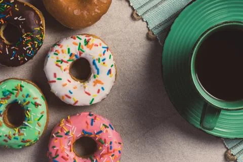 Donuts of different flavors accompanied by a cup with coffee for breakfast. Stock Photos