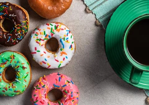 Donuts of different flavors accompanied by a cup with coffee for breakfast. Stock Photos