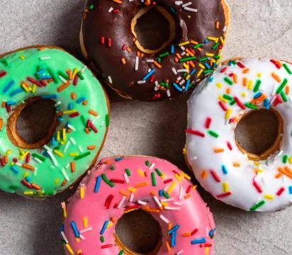 Donuts of different flavors accompanied by a cup with coffee for breakfast. Stock Photos