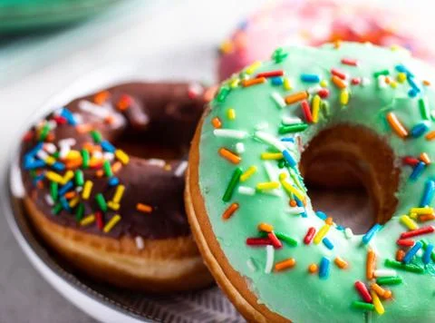 Donuts of different flavors accompanied by a cup with coffee for breakfast. Stock Photos