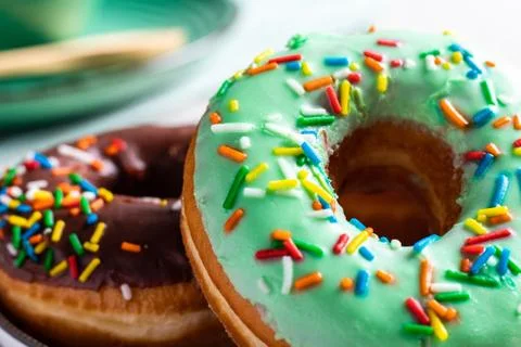 Donuts of different flavors accompanied by a cup with coffee for breakfast. Stock Photos