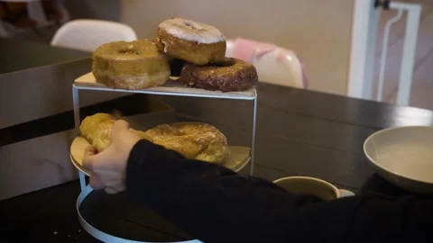 Donuts on display with coffee child hand takes donut Stock Footage 220089272