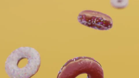 Donuts falling in slow motion. Yellow background. CInematic. Stock Footage 239537127