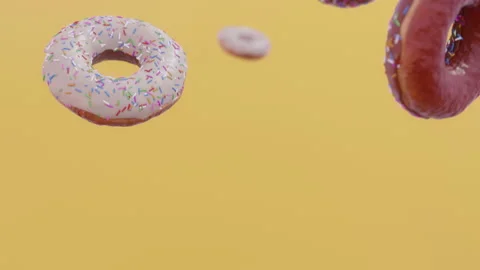 Donuts falling in slow motion. Yellow background. CInematic. Stock Footage 239537162