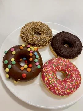 Donuts with multi-colored sprinkles on a white dish. Stock Photos