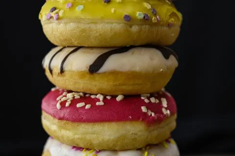 Donuts of multiple colors piled up close up Stock Photos