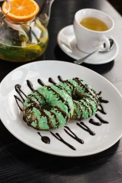 The donuts on the plate, kettle with herbal tea and tea Cup on black table Stock Photos