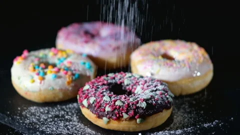 Donuts sprinkle with powdered sugar. Spreading Sugar Powder On Doughnuts Video stock 147093950