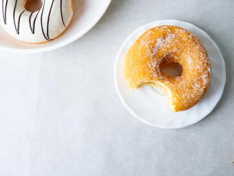 Donuts with sugar sprinkles with bite mark on a white background. Stock Photos