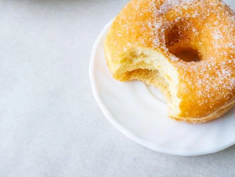 Donuts with sugar sprinkles with bite mark on a white background. Stock Photos