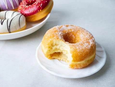 Donuts with sugar sprinkles with bite mark on a white background. Stock Photos