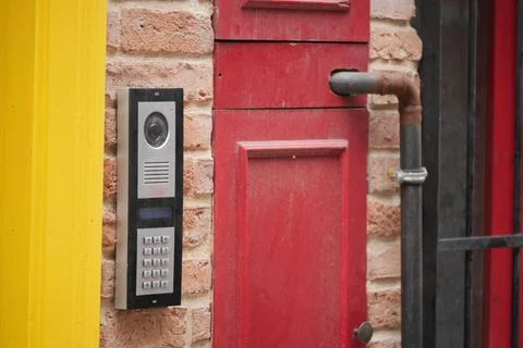 Door entry system next to yellow and red wall Stock Photos