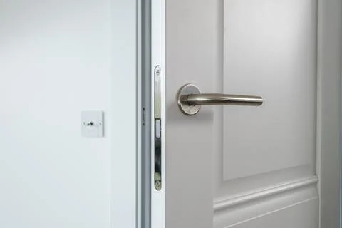 Door handle and light switch next to it in a bright room or office Stock Photos