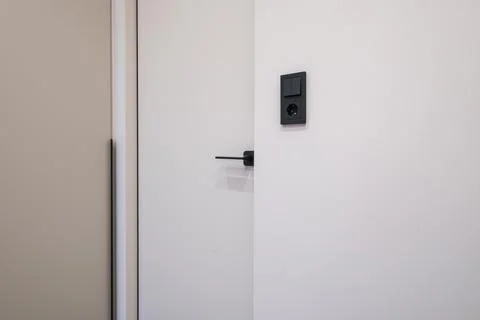 Door handle and light switch next to it in a bright room or office Stock Photos