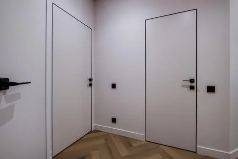 Door handle and light switch next to it in a bright room or office Stock Photos