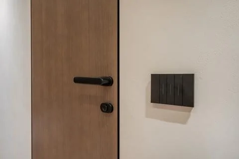 Door handle and light switch next to it in a bright room or office Stock Photos