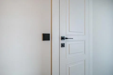 Door handle and light switch next to it in a bright room or office Stock Photos