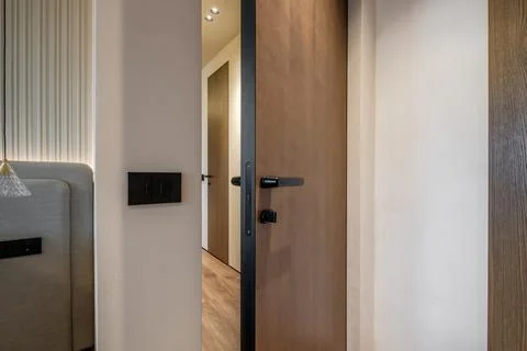 Door handle and light switch next to it in a bright room or office Stock Photos
